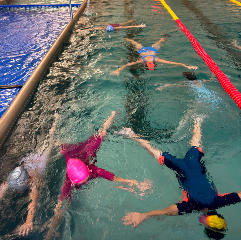 dzieci leżą na wodzie w pozycji „meduzy”