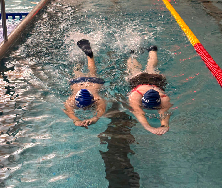 grupa dzieci pływa w płetwach z deskami w dłoniach